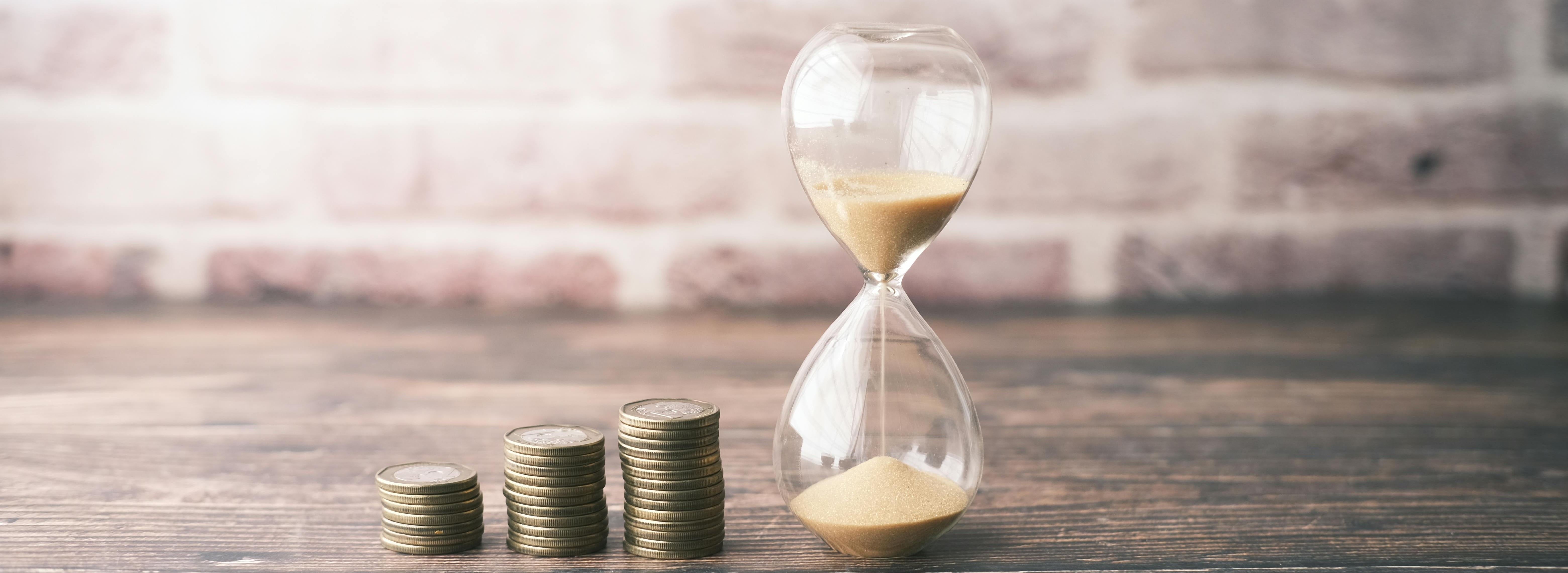 Hourglass with coins stacked next to it